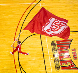 Student carrying flag on basketball court. Link to Beneficiary Designations.